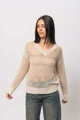 Buzo de hilo color beige, tejido calado con escote en V, silueta relaxed, puños y cintura acanalados.