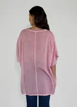 Blusa gris de lino y algodón, de corte amplio, con cuello redondo y mangas cortas con terminación desflecada. Presenta un volante diagonal en el frente.