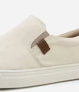 Championes slip on color crudo, con elásticos laterales y detalle de etiqueta marrón con logo en el lateral.