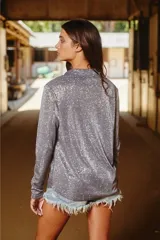 Camisa de manga larga color marrón con brillo, cuello clásico y cierre frontal con botones. Tejido de punto fino y corte holgado.