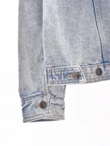 Campera de jean negra con botones metálicos, bolsillos frontales con solapa y cuello clásico.