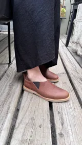 Zapato bajo color beige con textura de reptil, con detalle de cuero marrón en el talón.
