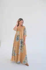 Vestido largo color camel con estampado de flores azules, corte amplio, escote en V y mangas 3/4.