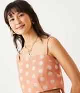 Blusa musculosa cropped color salmón con estampado de mandalas blancas, tirantes finos ajustables y lazo en la espalda.