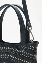 Cartera tote negra de cuero vacuno con tachas metálicas plateadas y doradas. Tiene doble asa corta y correa larga desmontable. Forro interior de algodón.