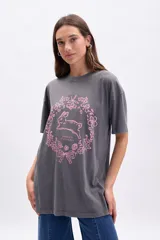 Remera gris oscuro de corte oversize con estampa de un conejo dentro de una corona de flores y la frase "Nature in Harmony" en color rosa.