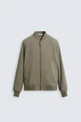 Cazadora bomber ligera gris confeccionada en tejido técnico. Cuello y puños en rib elástico, manga larga, bolsillos de vivo en cadera y bolsillo interior. Cierre frontal con cremallera.