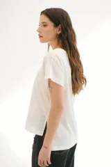 Blusa blanca con estampado de hojas en relieve, cuello redondo y mangas cortas.