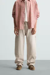 Pantalón gris de corte relaxed fit, con cinco bolsillos, efecto lavado, aplicación de tira y bolsillo multifunción en perneras. Cierre frontal con cremallera y botón.