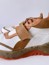 Zapatillas deportivas blancas con detalles en cuero color salmón y suela gruesa con detalles en naranja.