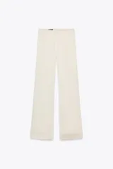 Pantalón de vestir color crema de tela satinada, corte palazzo y tiro alto.