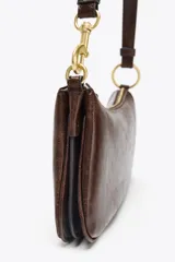 Bolso de hombro marrón oscuro con forma alargada y asa corta. Interior con tres compartimentos y bolsillo interior con cierre con cremallera. Asa de hombro con detalles metálicos dorados.