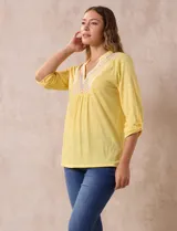 Blusa blanca de poliéster y rayón con escote en V bordado y mangas tres cuartos regulables con presilla y botón.
