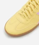 Championes color amarillo con detalles laterales en lila y talón en azul marino.