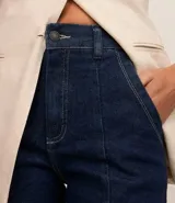 Bermuda de jeans azul oscuro, con cintura alta, trabillas, cierre con cremallera y botón, bajo ancho y bolsillos delanteros tipo cuchillo.