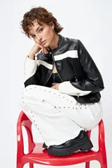 Pantalón de denim blanco con calce wide leg y ruedo desflecado. Presenta tachas metálicas a lo largo de los laterales.
