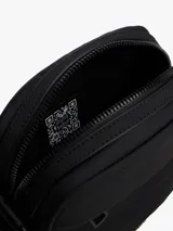 Bandolera Tommy Hilfiger negra con correa ajustable, cierre de cremallera, bolsillo interior abierto, bolsillo exterior con cremallera y logo metálico en el frente.