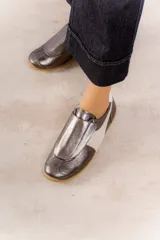 Zapatillas deportivas plateadas con detalles en blanco y suela color caramelo.