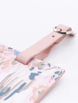 Identificador de maleta rectangular con estampado floral en tonos pastel y correa de ajuste rosa.