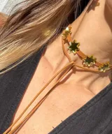 Gargantilla marrón con dije de estrellas doradas.