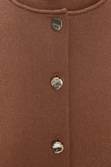 Top marrón de tejido de punto, con cuello redondo y sisa. Cierre frontal con botones.