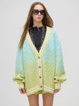 Cardigan tejido de punto con patrón de rombos en degradé de grises y blanco. Tiene corte oversize, mangas largas y cierre frontal con botones.