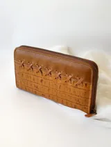 Billetera de cuero color camel con cierre metálico, diseño con textura símil piel de cocodrilo y detalle de costuras cruzadas en el frente. Incluye monedero interno y espacio para billetes extendidos.