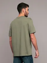 Remera verde militar de algodón, con cuello redondo y logo de Calvin Klein estampado en el pecho dentro de un recuadro blanco.