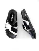 Sandalias con tiras cruzadas de cuero con estampado de vaca, suela plana y plantilla de cuero negra con logo de la marca.