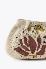 Bolso de mano pequeño confeccionado en hilatura de algodón color beige, con bordado de flores en marrón y negro, aplicación de abalorios y cierre con clip.