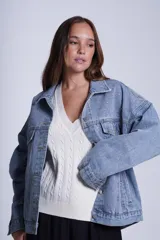 Campera clásica de jean celeste con cuello camisero, bolsillos frontales con solapa y cierre con botones metálicos. Presenta detalles de pequeños brillos blancos dispersos en la parte delantera y las mangas.