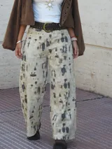 Pantalón de jean recto y ancho, de tiro medio, con estampado de manchas irregulares en tonos beige y gris oscuro.
