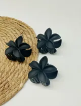 Pinza para el pelo negra con forma de flor de cinco pétalos.