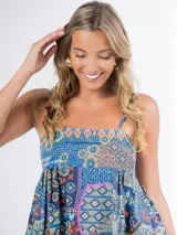 Vestido largo de algodón con estampado geométrico multicolor, corte cuadrado, elástico en la espalda y tirantes finos. Incluye aplique de flor desmontable.