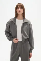 Campera gris de manga larga con cierre frontal, cuello alto y vivos blancos en los hombros y mangas.