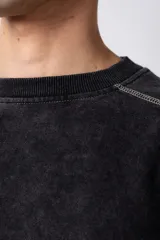 Buzo negro de frisa 100% algodón, con calce oversize y lavado gastado. Tiene costuras a contratono y recortes.