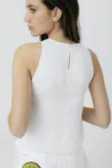 Musculosa blanca con cuello redondo y botones dorados en los laterales.