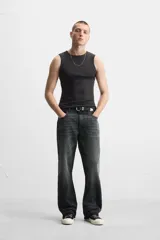 Pantalón de jean negro con efecto lavado, corte flare, cinco bolsillos, cierre frontal con cremallera y botón, y bajo con acabado irregular.