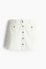 Minifalda evasé de denim color blanco, de tiro alto con botonadura frontal y bolsillos decorativos con solapa y botón.
