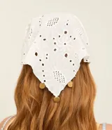 Pañuelo triangular confeccionado en tejido de laise (broderie) de algodón blanco, con bordados calados y pequeñas medallas metálicas decorativas.