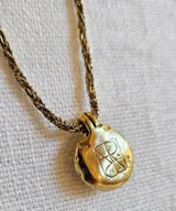 Collar con cadena de eslabones dorados y dije redondo con piedra amatista engarzada en metal dorado.