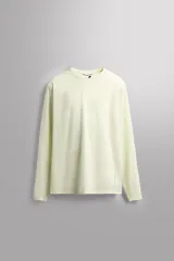 Camiseta deportiva color verde claro, de tejido técnico perforado, ligero y elástico. Tiene cuello redondo, mangas largas y costuras overlock.
