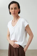 Remera color durazno con cuello en V y detalle de trenza en el escote.