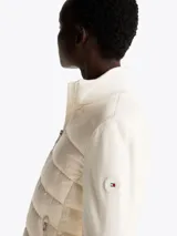 Chaleco acolchado color blanco con cuello alto, cierre frontal con cremallera, dos bolsillos laterales con cremallera y parche con logo en el pecho.