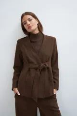 Chaqueta corta color beige, entallada, con escote en V, manga larga y cierre frontal con lazo fijo. Confeccionada en lana fina sin teñir, con bolsillos escondidos y terminaciones enviadas. Hecha 100% en Uruguay.