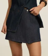 Short pollera de jeans azul oscuro, de cintura alta, con botón metálico en forma de flor y confeccionado con algodón BCI.