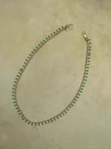 Collar dorado con cadena fina y pequeñas cuentas colgantes.