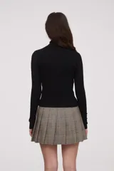 Polera de punto negro con cuello alto y manga larga, con diseño acanalado y ajuste ceñido.