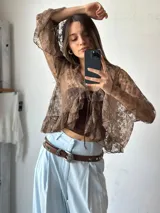 Blusa marrón de encaje con volados, mangas acampanadas y lazo en el escote.