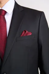 Traje de vestir azul marino, compuesto por saco de dos botones con solapa de muesca, dos bolsillos laterales con solapa y un bolsillo de ojal en el pecho, y pantalón de vestir con corte recto. Incluye camisa blanca, corbata celeste y pañuelo de bolsillo blanco con borde celeste.